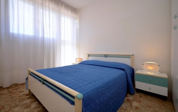 A bedroom with a bed, bedside tables, and a window with curtains.