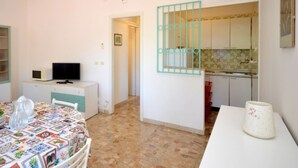A compact living space with a dining area, a kitchenette, and a TV on a small cabinet.