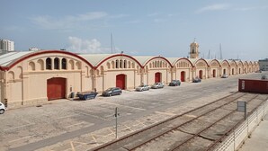 Une longue rangée de bâtiments beiges, avec des portes rouges et un clocher.