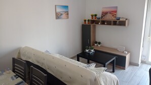 Une petite pièce, bien rangée, avec un lit, un bureau et une étagère ornée de plantes.