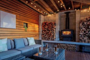 A cozy outdoor seating area with a sofa, cushions, and a table with glasses.
