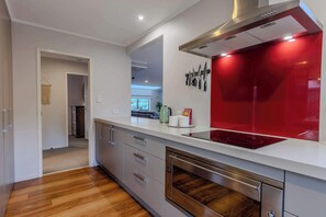 A modern kitchen with a stainless steel range hood, a red backsplash, and a built-in dishwasher.