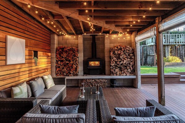 An outdoor seating area with a fireplace, wooden walls, and string lights.