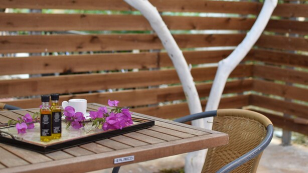 A wooden table with a tray holding two bottles, a cup, and purple flowers.