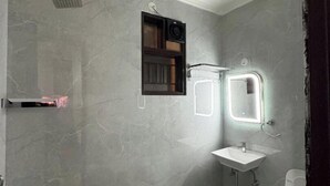 A bathroom with a white sink, a mirror, a shower, and a toilet. - Radiant Blu Hotels Sector 70 (Noida)