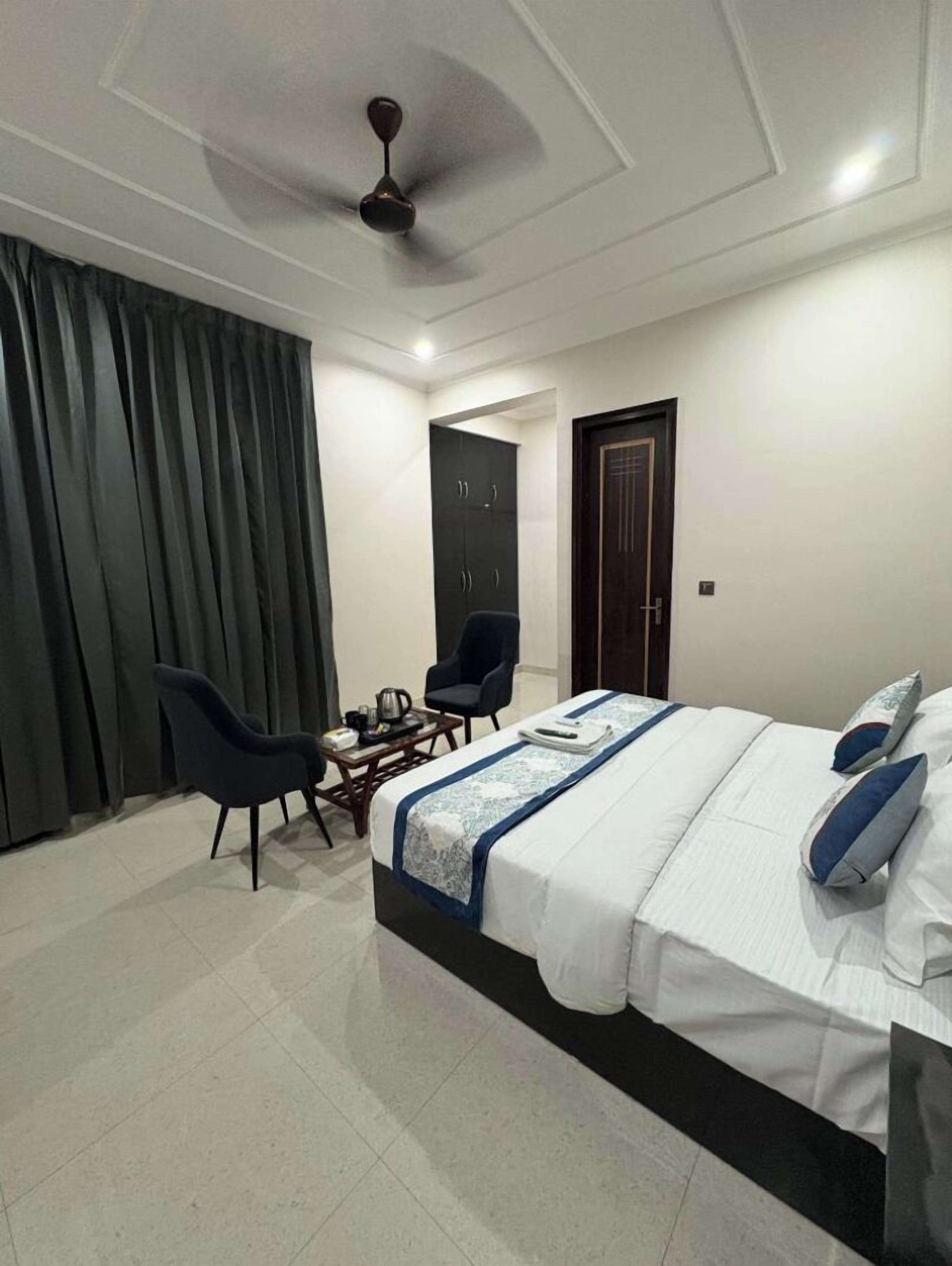 Un dormitorio moderno con cama, dos sillas, una mesita, un armario y un ventilador de techo.