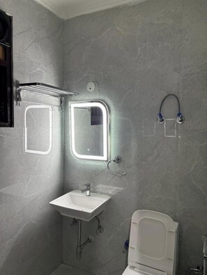 A bathroom with a white sink, two mirrors, a towel rack, and a toilet.