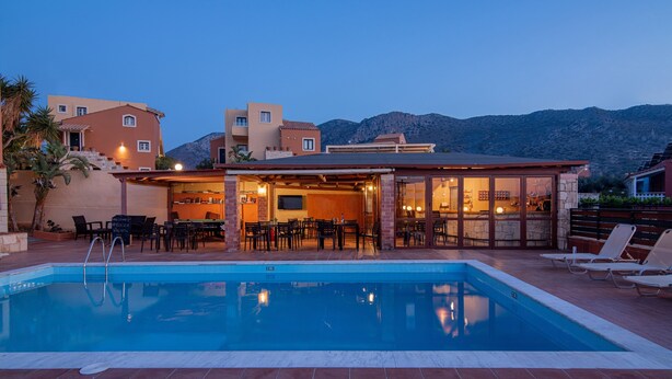 Una piscina con sillas de descanso, una zona de bar y vistas a las montañas.