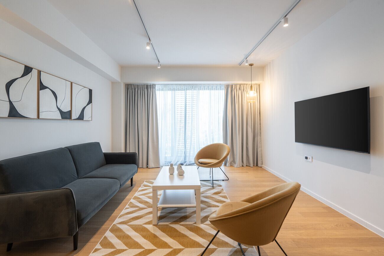 A modern living room with a sofa, a coffee table, a TV, and a chair.