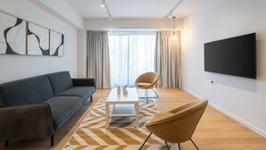 A modern living room with a sofa, a coffee table, a TV, and a chair.