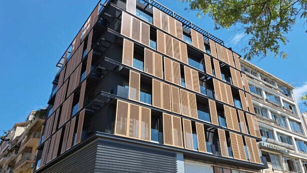 A modern multi-story building with a mix of balconies and large windows.