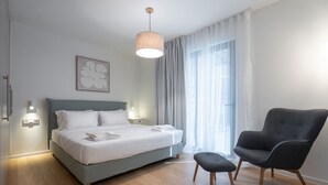 A modern hotel room with a bed, a chair, and a window with curtains.