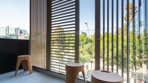 A modern room with large windows, a small stool, and a round table.