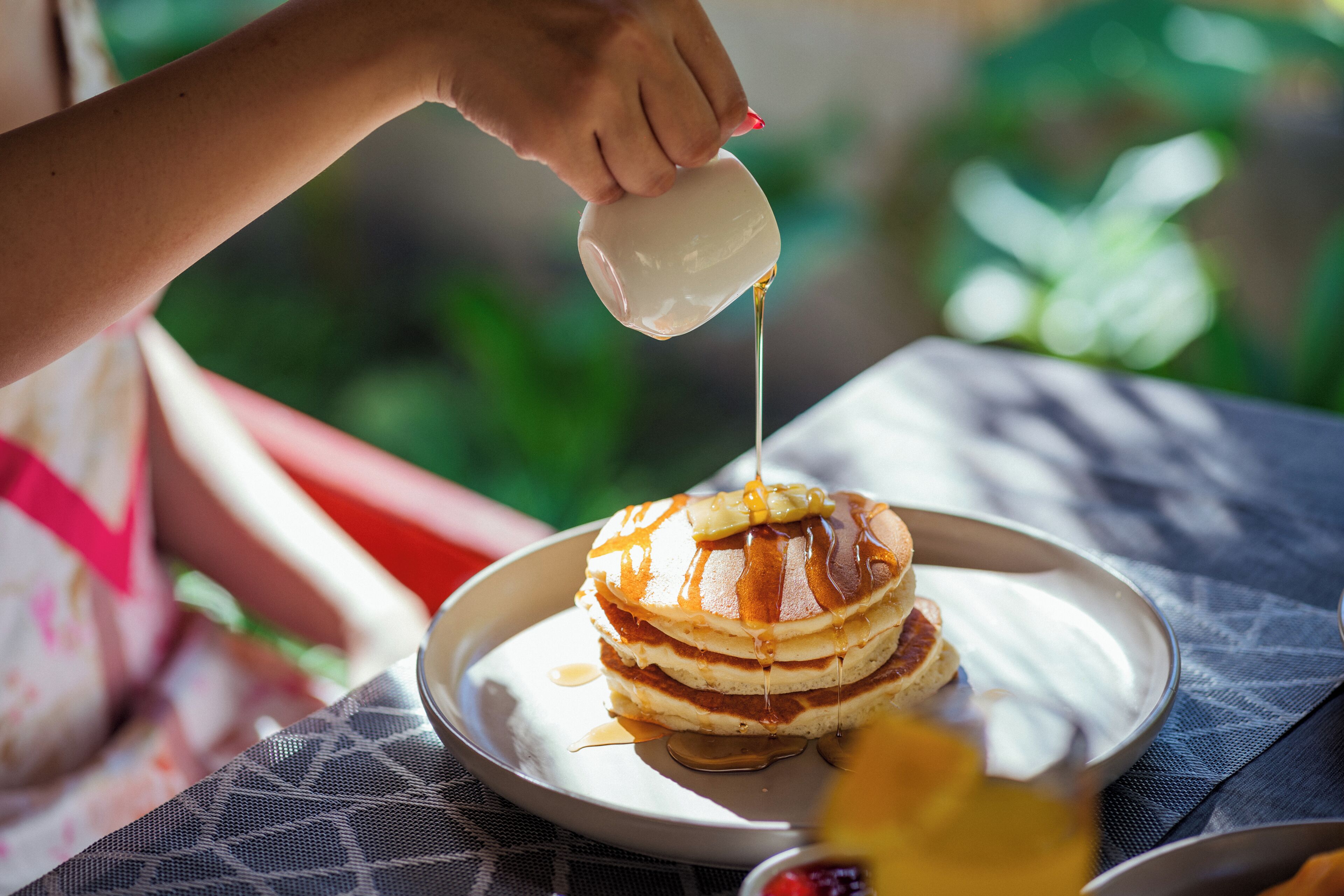 Une pile de crêpes arrosées de sirop.