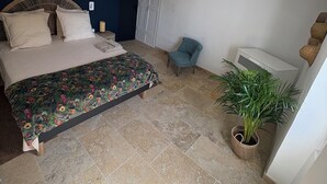 A bedroom with a bed, a chair, a potted plant, and a ceiling with exposed beams. - Charming village house with sauna (Bédoin)