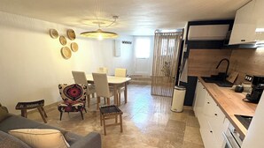 A compact living space with a dining area, a kitchen, and a seating area with a lamp. - Charming village house with sauna (Bédoin)
