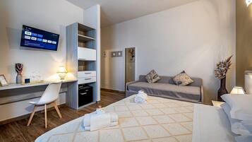 Ein modernes Hotelzimmer mit einem Bett, einem Schreibtisch mit Computer, einem Fernseher und einer Couch.