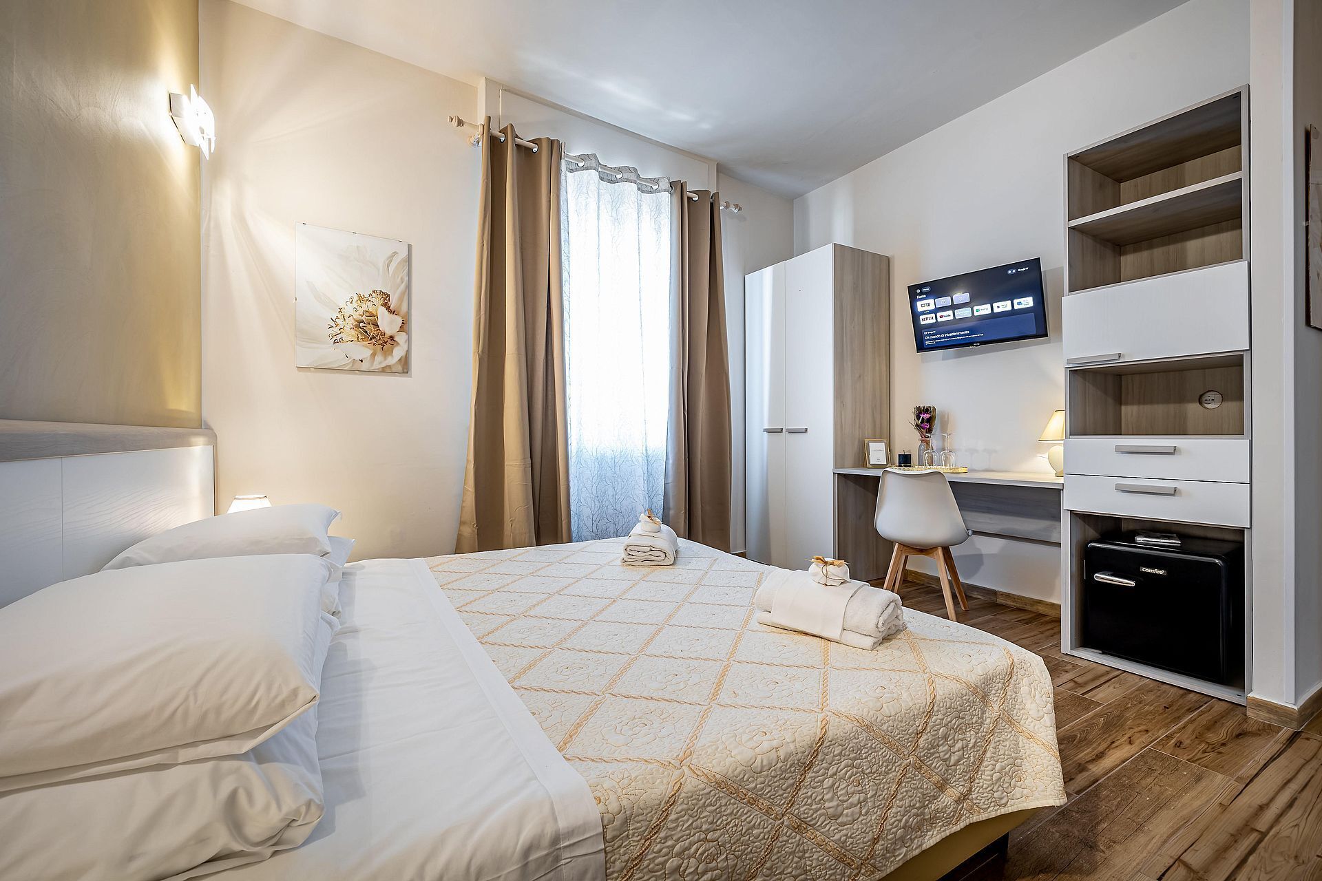 Una habitación de hotel con cama, escritorio, televisor y armario.