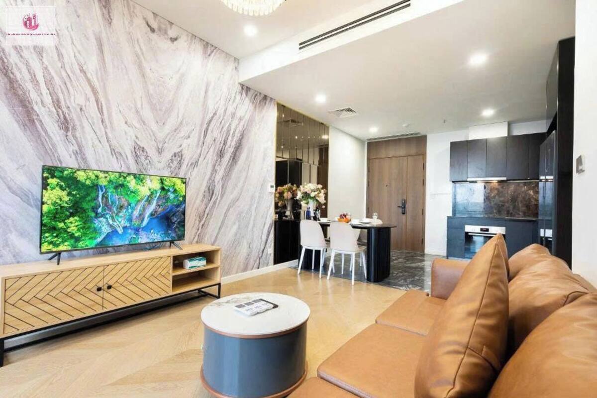 Un salon moderne comprenant un téléviseur, un canapé et un coin repas avec des chaises et une table.