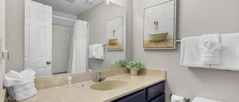 Een badkamer met een beige wastafel, donkere kastjes, een grote spiegel en een toilet.