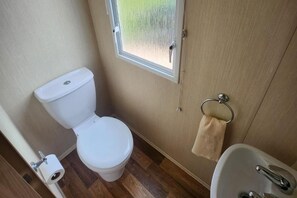 Un baño pequeño con inodoro, lavamanos y ventana.