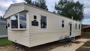A mobile home with a sign reading "OWNER'S ENGINEER HORIZON 36 x 12.3 ft." It has a covered patio area with outdoor seating. - Petfriendly- Familyfriendly- 8berth- Tattershall (Lincoln)