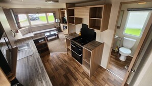 A compact RV kitchen with a stove, sink, and a small dining area. - Petfriendly- Familyfriendly- 8berth- Tattershall (Lincoln)