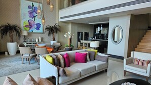 Ein großzügiger Wohnbereich mit einem modernen Sofa, einem Esstisch und einer Küche im Hintergrund.