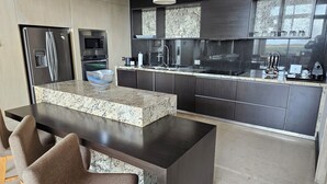 Eine moderne Küche mit dunklen Schränken, einer Granit Arbeitsplatte, Edelstahlgeräten und einem Essbereich mit zwei Stühlen.