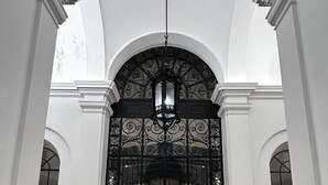A grand hallway with high ceilings, white columns, and a large ornate gate. - AD Vatican Luxury Rooms (Rome)