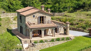 Une maison en pierre avec un toit en tuiles, un balcon et une terrasse couverte.