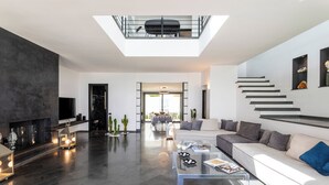 Uma sala de estar moderna com uma mesa de centro de vidro, um sofá e uma escada.
