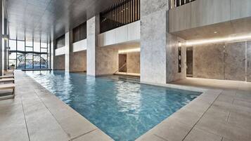 Una piscina interior con vista despejada del techo y las paredes, ventanas amplias y un diseño arquitectónico moderno.