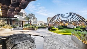 A modern outdoor space with a stone pathway, green seating areas, and a unique spherical structure. - Executive Suite with Rare Oversized Terrace, Heated Pool, Gym, Sauna, Steam (Melbourne)