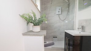 A modern bathroom with a shower, a sink, and a potted plant. - The Tinystore (Bodmin)