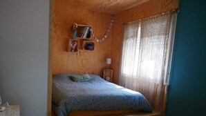 A cozy bedroom with a built-in bed, wooden shelves, and a window with sheer curtains. - Villa in the shade of the pines, 5 minutes from the beach. (Lacanau)