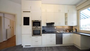A modern kitchen with white cabinetry, stainless steel appliances, and a large window providing natural light. - Spacious Zurich Apt, Huge Terrace & Views (Zürich)