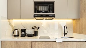 Una cocina moderna con microondas integrado, cafetera y lavamanos.