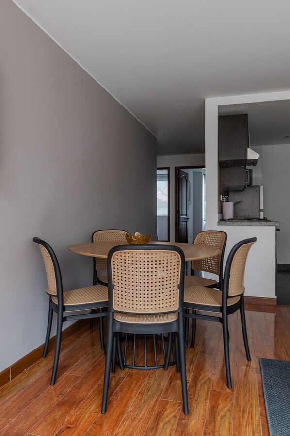 A dining area with a round table and four chairs, a kitchen area with a sink and stove, and a door leading to another room.