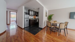 A modern kitchen with dark cabinets, a central island, and a dining area with wicker chairs and a table. - Bright 3BR @Commercial district with private terrace (Bogotá)