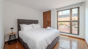 A modern bedroom with a large bed, a wooden wardrobe, and a view of the outdoor patio through a sliding door. - Bright 3BR @Commercial district with private terrace (Bogotá)