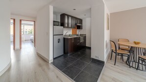 Une cuisine moderne avec des meubles de couleur sombre, un four à micro-ondes et un coin repas comprenant une table ronde et des chaises.