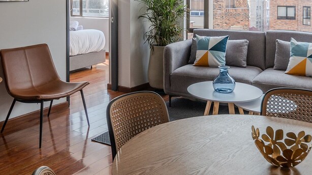 A modern living room with a sofa, chairs, a dining table, and a large window with a city view. - Spectacular 4BR @Financial and Commercial Zone (Bogotá)
