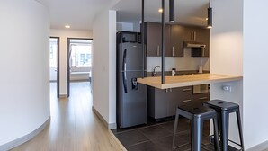 A modern kitchen with a built-in refrigerator, a microwave, and a wooden countertop. There are two black bar stools and a hanging light fixture. - Relaxing 3BR @Commercial Area near Zona G (Bogotá)