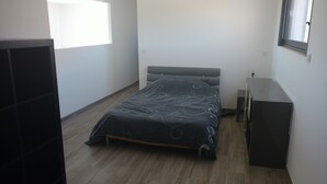 Un dormitorio con cama, cómoda, ventana y puerta.