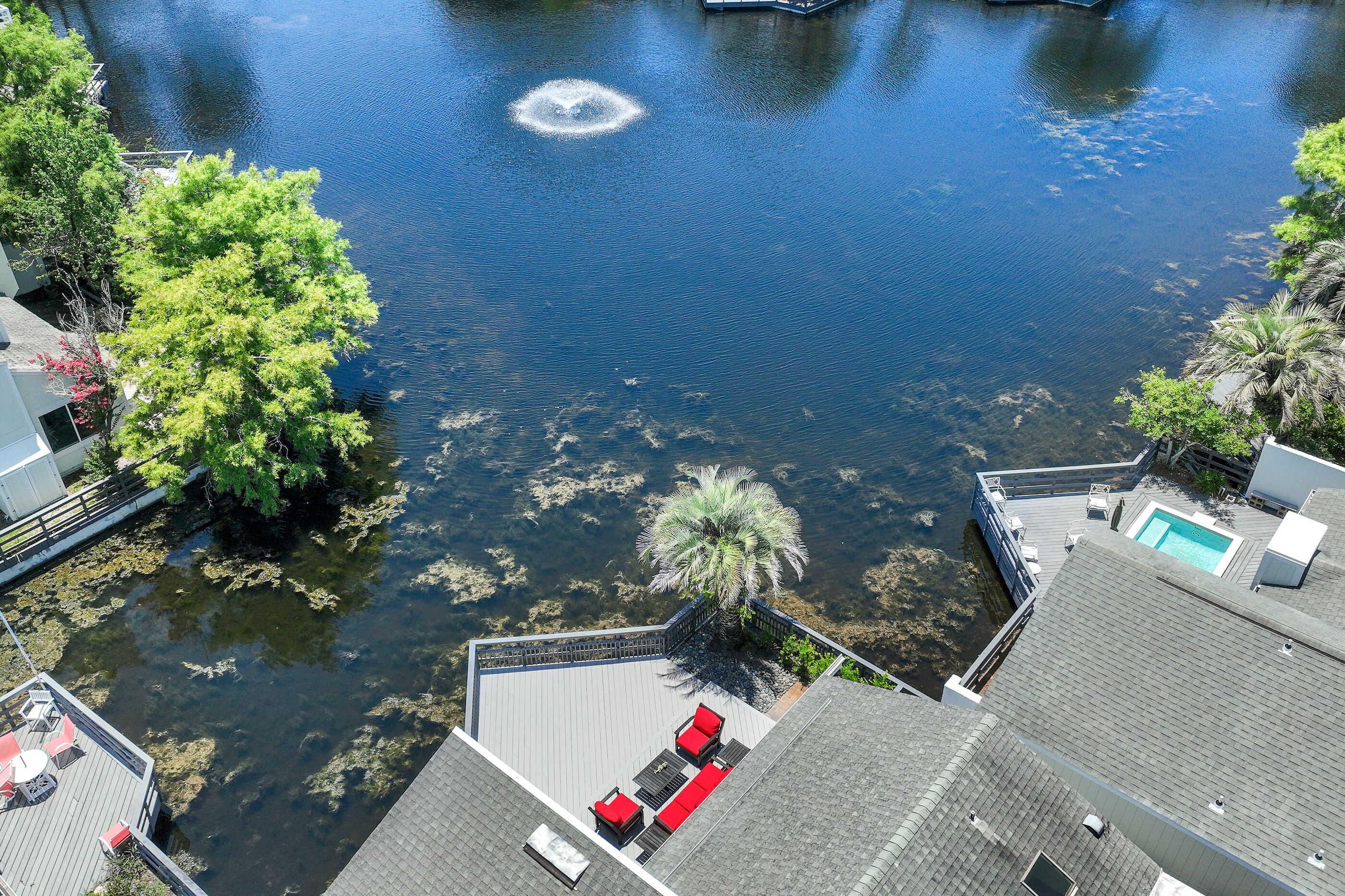 A high vantage view of a waterfront property with a pool, outdoor seating, and a dock.