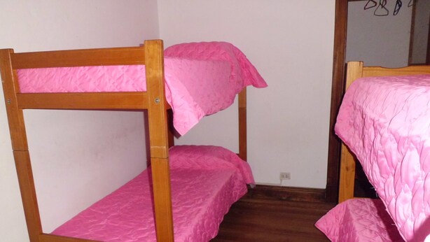A bunk bed with pink bedding in a room with wooden flooring and white walls. - Hostel Casa la Red (Mar del Plata)