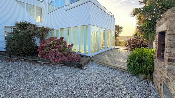 A modern house with a sloped roof, large windows, and a gravel driveway.