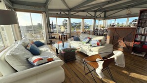 A spacious living area with a high ceiling, large windows, and a view of the city.