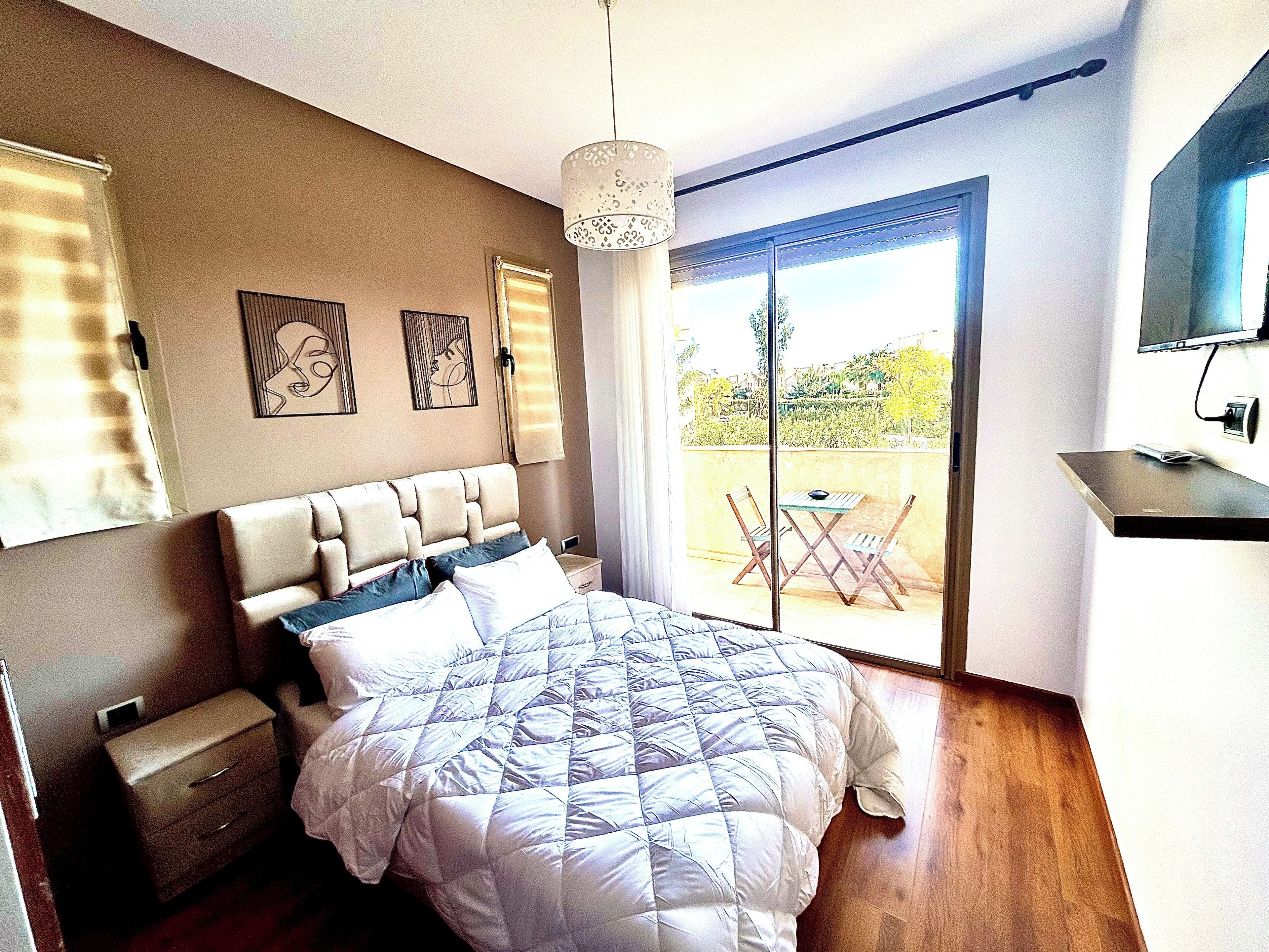 Une chambre à coucher avec un lit, une table de chevet et une vue sur l’extérieur.